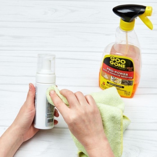 limpar uma garrafa manualmente com um pano. ao lado uma garrafa de plástico com tampa de spray