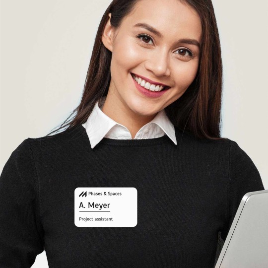 Mulher com camiseta azul e cracha adesivo retangular personalizado indicando nome e função.