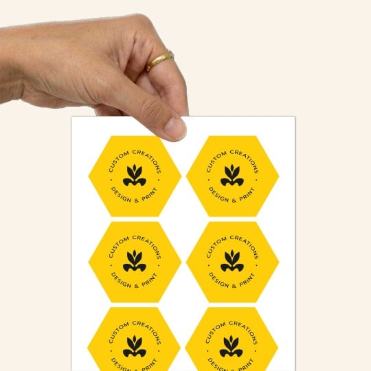  Uma mão que segura uma folha de etiquetas hexagonais amarelas e pretas.