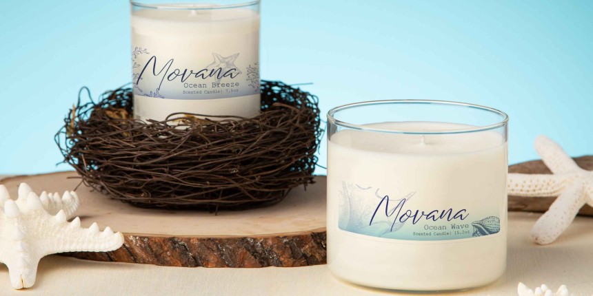 Dois porta-velas com velas brancas com etiquetas adesivas personalizadas e objetos marinhos decorativos ao fundo