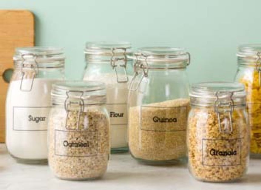 Potes de vidro para alimentos com cereais e etiquetas adesivas transparentes que indicam o conteúdo do pote