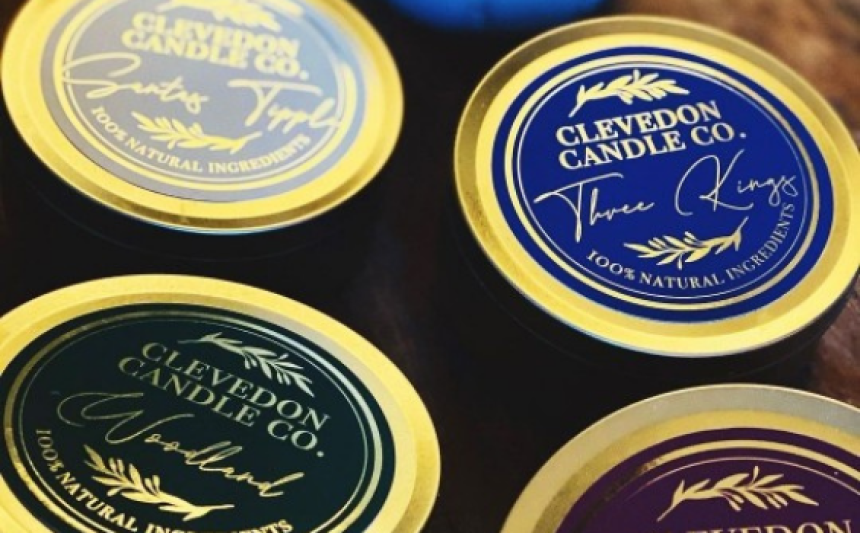 Quatro etiquetas azuis redondas em papel dourado com a inscrição "Clevedon Candle" escrita em potes de vela