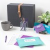 Mesa com itens sobre ela, incluindo envelopes azul-claros e roxos com etiquetas de remessa retangulares personalizadas