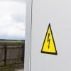 Etiqueta triangular amarela com símbolo de raio indicando perigo de corrente elétrica. Anexado ao painel elétrico