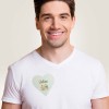Um homem vestindo uma camiseta branca com cracha adesivo seda de acetato em forma de coração feito de acetato de seda